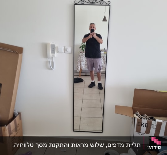 תמונה של אדם מצולם במראה עם קופסאות מסביב